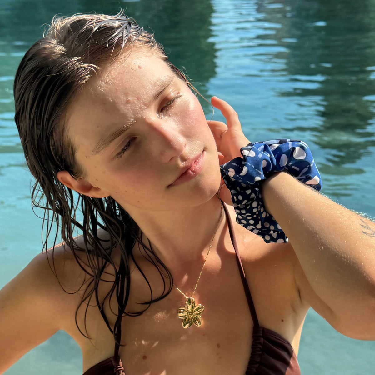 Woman with wet hair after a swim, wearing a recycled scrunchie by the sea